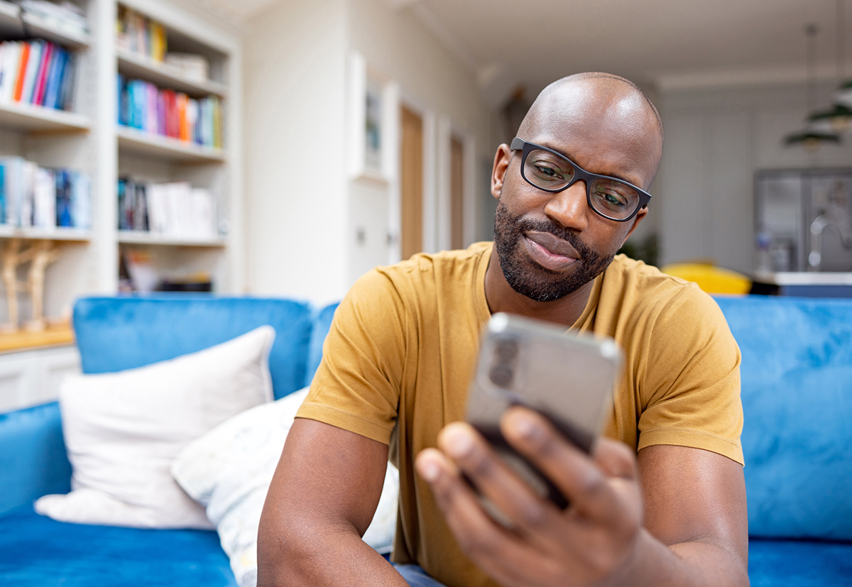 Man looking at his phone, sitting on a couch