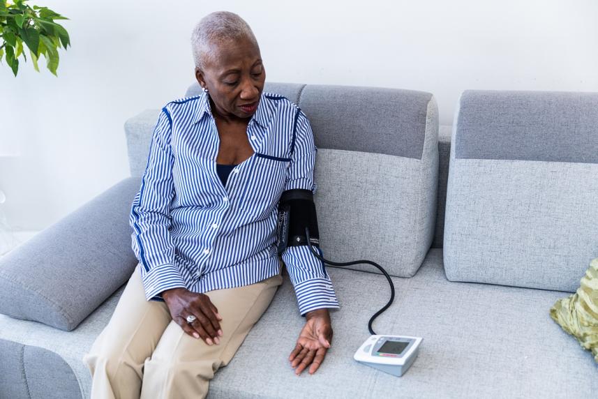 Woman measuring her blood pressure at home, on her couch