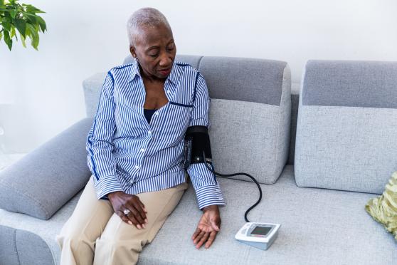 Woman measuring her blood pressure at home, on her couch